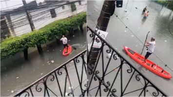 Homem pratica stand-up paddle em rua alagada de Fortaleza em manhã de fortes chuvas